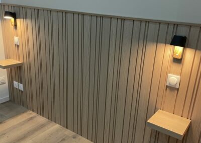 Tête de lit en panneaux de bois avec tablettes et éclairage intégré.